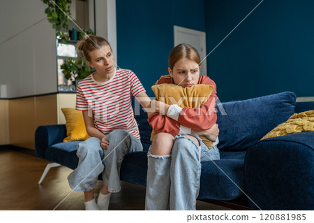 Affectionate mom is trying to establish contact with teenage daughter sitting on couch at home. Affectionate mom is trying to establish contact with teenage daughter sitting on couch at home. 120881985