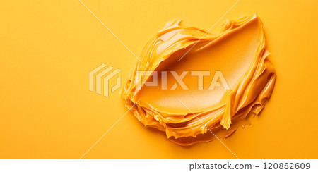 Smooth, creamy peanut butter is swirled beautifully on a bright yellow background, showcasing its rich texture and inviting color. This appetizing display emphasizes the natural appeal of the spread. 120882609