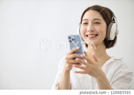 Young woman listening to music on headphones Young woman listening to music on headphones 120883591