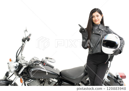 騎自行車的女孩站在自行車旁邊,拿著頭盔指著 騎自行車的女孩站在自行車旁邊,拿著頭盔指著 120883948