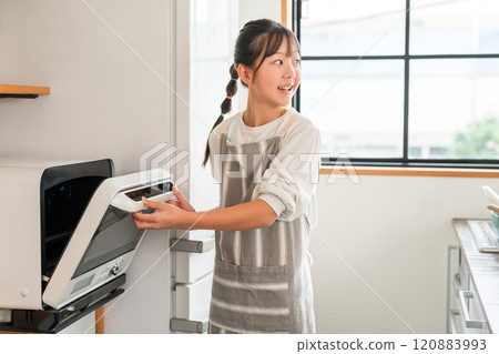 Children/girls (elementary school/junior high school students) using a microwave in the kitchen at home Children/girls (elementary school/junior high school students) using a microwave in the kitchen at home 120883993