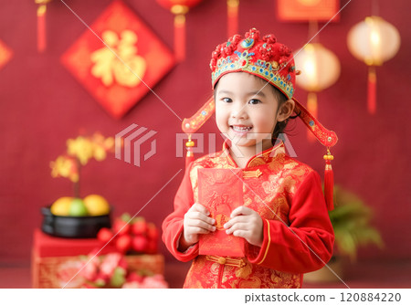 Joyful celebration, child in traditional attire holding red envelope for lunar new year 120884220