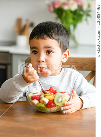 Child enjoying healthy fruit breakfast with fresh kiwi and berries in kitchen Child enjoying healthy fruit breakfast with fresh kiwi and berries in kitchen 120884469