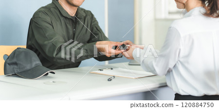 A male mechanic and a female customer serving at the reception desk of an auto repair shop 120884750