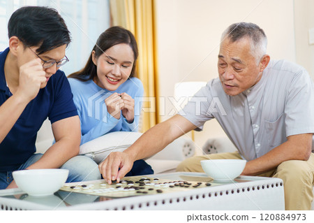 Happy cheerful Asian family spending time to play Go Game together in weekend. Daughter and son enjoy are playing board game with their father. Family's activities with senior elder adult. 120884973