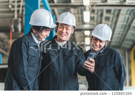 Male worker in work clothes using a smartphone (logistics center, factory, distribution center) 120885164