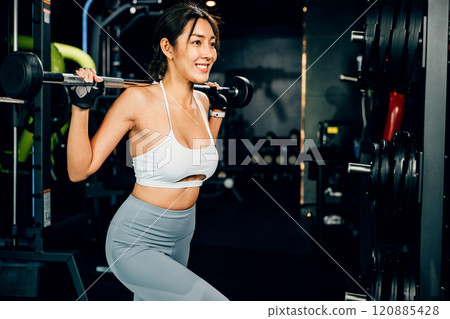 Asian woman muscular guy squat exercise with a lifting barbell in gym, female exercising squatting performing shoulder press lift weight for legs at fitness gym, workout healthy lifestyle concept Asian woman muscular guy squat exercise with a lifting barbell in gym, female exercising squatting performing shoulder press lift weight for legs at fitness gym, workout healthy lifestyle concept 120885428