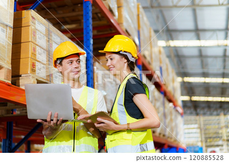 Caucasian male and female warehouse personnel engage in amicable conversation, culminating in a cordial handshake. 120885528