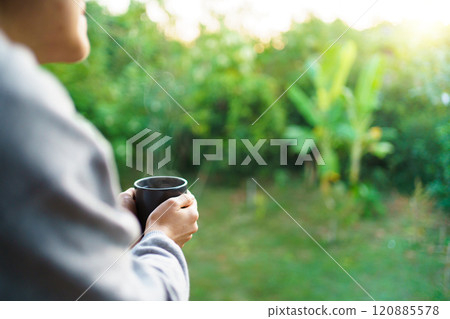 Unrecognizable Asian woman enjoy drinking a coffee at the corridor with the rural environment background and beautiful sunlight in the morning. Delighted Asian woman drinking a hot coffee in morning. Unrecognizable Asian woman enjoy drinking a coffee at the corridor with the rural environment background and beautiful sunlight in the morning. Delighted Asian woman drinking a hot coffee in morning. 120885578