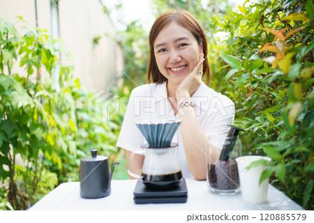 Happy Asian beautiful woman making a specialty coffee in morning at her backyard garden, woman brewing a coffee by dripping or pouring over a hot water. Happy Asian beautiful woman making a specialty coffee in morning at her backyard garden, woman brewing a coffee by dripping or pouring over a hot water. 120885579