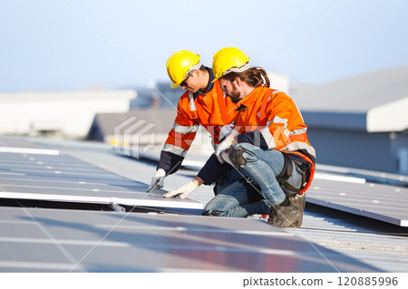 Professional electric engineers survey and inspect solar panels installation on the factory metal sheet roof top, electric engineer team inspecting and check solar cell system. 120885996