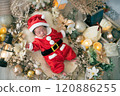 A 0-month-old newborn baby wearing Santa clothes for a Christmas photo shoot 120886255