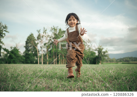 happy toddle baby girl running on grass field 120886326