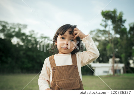 worried toddle baby girl on grass field worried toddle baby girl on grass field 120886327
