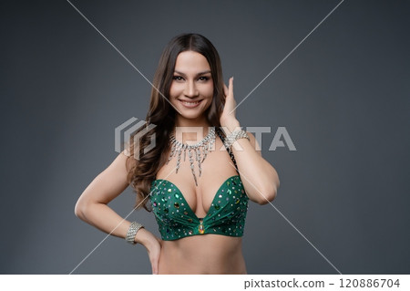 Belly dancer performing with vibrant green costume in studio setting 120886704