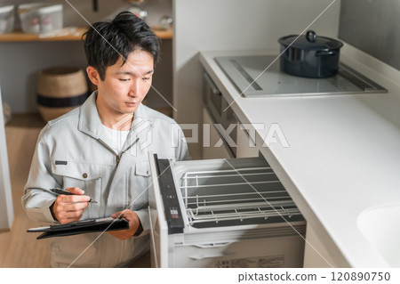 A male businessman in work clothes diagnoses, checks, and assesses the dishwasher and dishwasher in the kitchen. 120890750