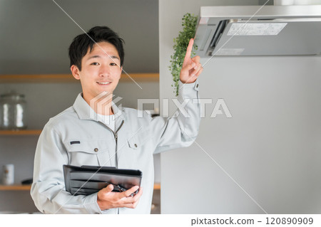 一位穿著工作服的男商人檢查廚房的抽油煙機和換氣扇。 120890909