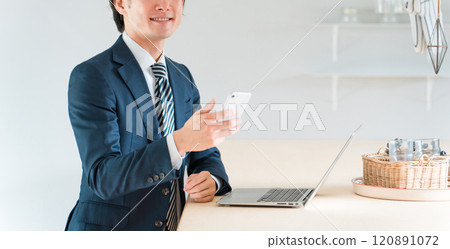 Asian businessman in a suit working on a computer at a dining table Asian businessman in a suit working on a computer at a dining table 120891072