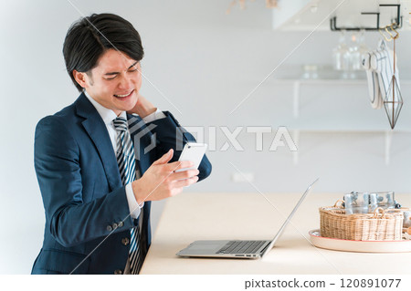Asian businessman looking at his smartphone and feeling depressed or disappointed (pinch, mistake, disappointment, carelessness, failure) 120891077