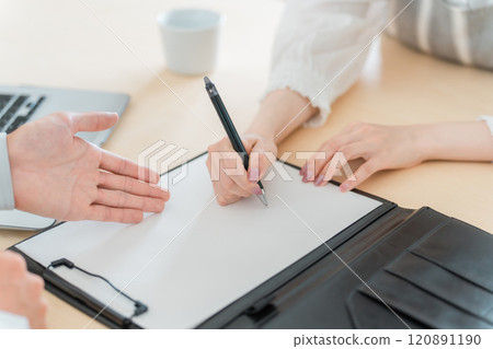 家庭主婦/婦女的手與穿著工作服的男性推銷員簽署合約/協議表，要求其簽名 120891190