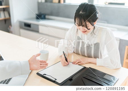 一位家庭主婦/女士與一位身穿工作服的男性推銷員簽署了一份合約/協議書，後者要求他簽字。 120891195