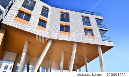 Modern high-rise apartment building  in white, stand tall against a blue sky, exemplifying innovative urban architecture with sleek, angular designs. 120891231