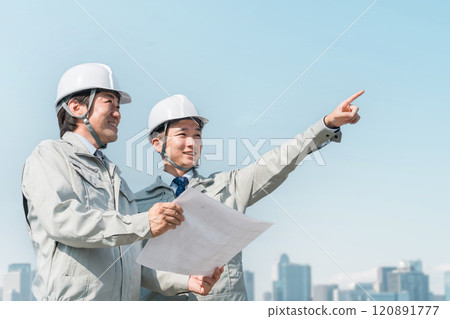 穿著工作服的工人在藍天下看藍圖(建築、建築、設計、房地產、土木工程、施工、現場監工) 穿著工作服的工人在藍天下看藍圖(建築、建築、設計、房地產、土木工程、施工、現場監工) 120891777