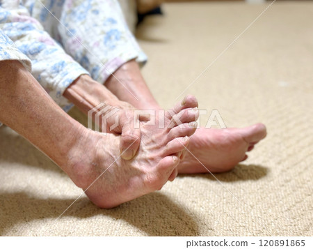一位老婦人的手壓著穿著睡衣的腳背 120891865