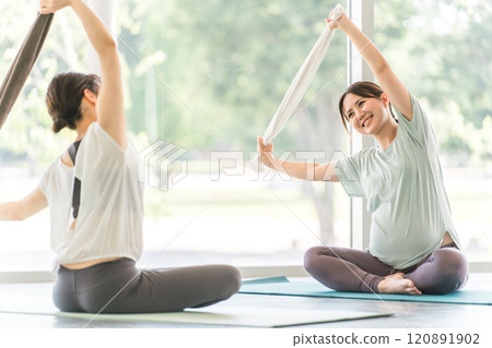 Young pregnant woman doing maternity yoga in yoga class with towel Young pregnant woman doing maternity yoga in yoga class with towel 120891902
