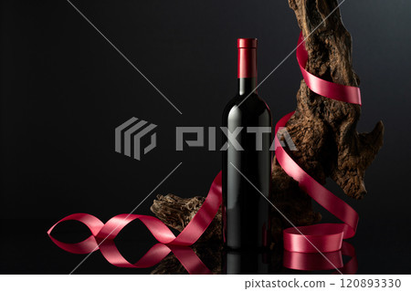 Bottle of red wine on a black reflective background. 120893330
