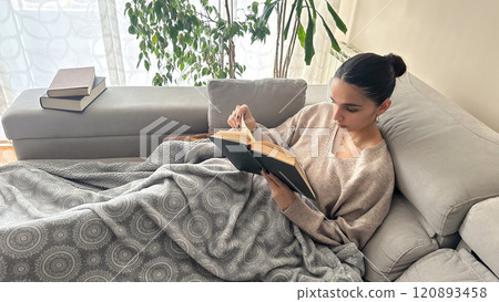 A young teenager immersed in reading on a pleasant afternoon on the couch 120893458