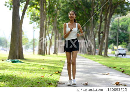 Young sporty woman jogging through a tranquil park in the morning. Healthy lifestyle concept Young sporty woman jogging through a tranquil park in the morning. Healthy lifestyle concept 120893725