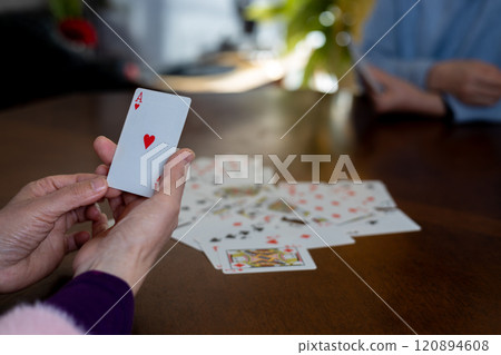 Woman's hand holding the ace of hearts playing card 120894608