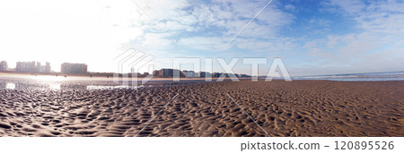 Vast Sandy Beach With City Skyline and Blue Sky 120895526