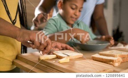 Crop woman applying butter on bread with brother whisking egg yolk in background Crop woman applying butter on bread with brother whisking egg yolk in background 120895641