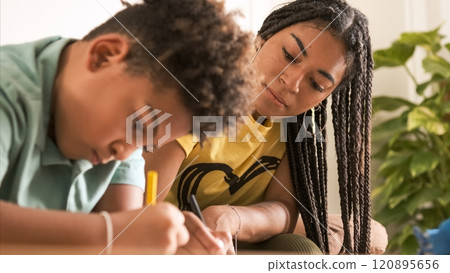 Young woman coloring with little brother in living room at home Young woman coloring with little brother in living room at home 120895656