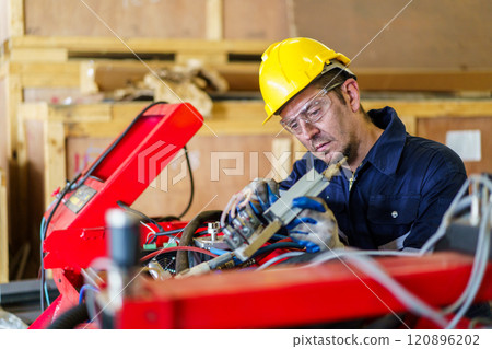Senior professional electrical or industrial engineer inspecting and repairing a robotic system in the manufacturing factory close up. Robotic technician repairing - fixing a automated machine. Senior professional electrical or industrial engineer inspecting and repairing a robotic system in the manufacturing factory close up. Robotic technician repairing - fixing a automated machine. 120896202