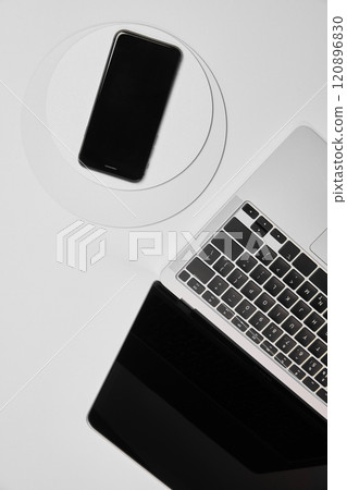 Close-up of laptop and smartphone on white surface. Negative space for showcasing apps or logos. Sleek and simple for promoting tech brands. Close-up of laptop and smartphone on white surface. Negative space for showcasing apps or logos. Sleek and simple for promoting tech brands. 120896830