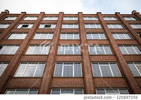 Brick building facade with large white framed windows 120897356