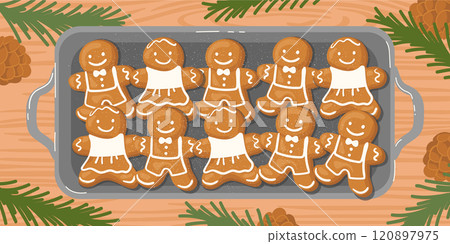 A baking tray with hot gingerbread cookies on the table, surrounded by fir branches and pinecones. 120897975