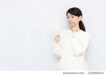 Middle-aged woman checking her skin Middle-aged woman checking her skin 120898828