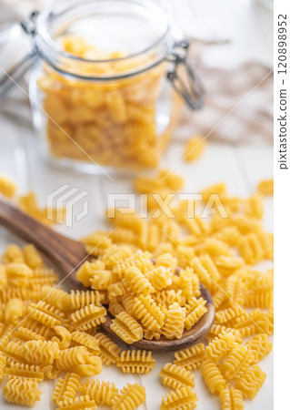 Uncooked italian pasta. Radiatori pasta in spoon on white table. 120898952