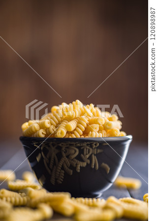 Uncooked italian pasta. Fusilli pasta in bowl on black table. Uncooked italian pasta. Fusilli pasta in bowl on black table. 120898987