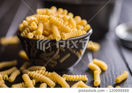 Uncooked italian pasta. Fusilli pasta in bowl on black table. 120898988