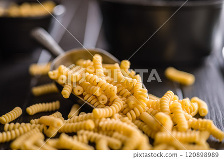 Uncooked italian pasta. Fusilli pasta in scoop on black table. 120898989