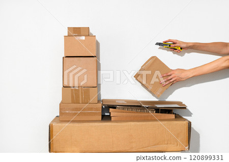 Pile of Cardboard Boxes and hand with cutter in Minimalist Setting Pile of Cardboard Boxes and hand with cutter in Minimalist Setting 120899331