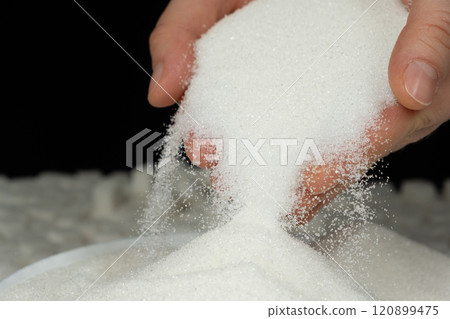 Hands pouring white crystalline refined sugar, black background Hands pouring white crystalline refined sugar, black background 120899475