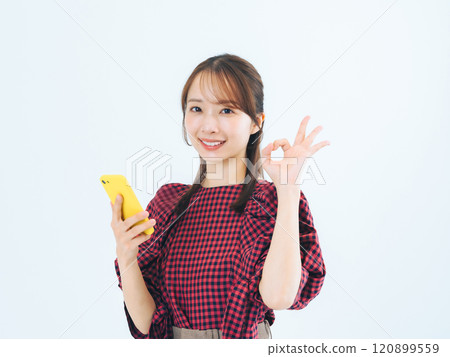 一位女士拿著智慧型手機並展現出 OK 的手勢 一位女士拿著智慧型手機並展現出 OK 的手勢 120899559