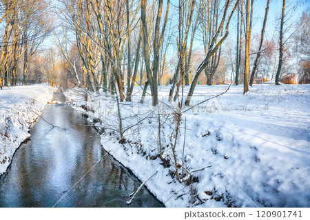 Breathtaking landscape in city park with snowy trees and beautiful reflection in frozen river. 120901741