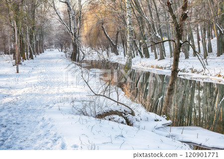 Outstanding landscape in city park with snowy trees and beautiful reflection in frozen river. Outstanding landscape in city park with snowy trees and beautiful reflection in frozen river. 120901771